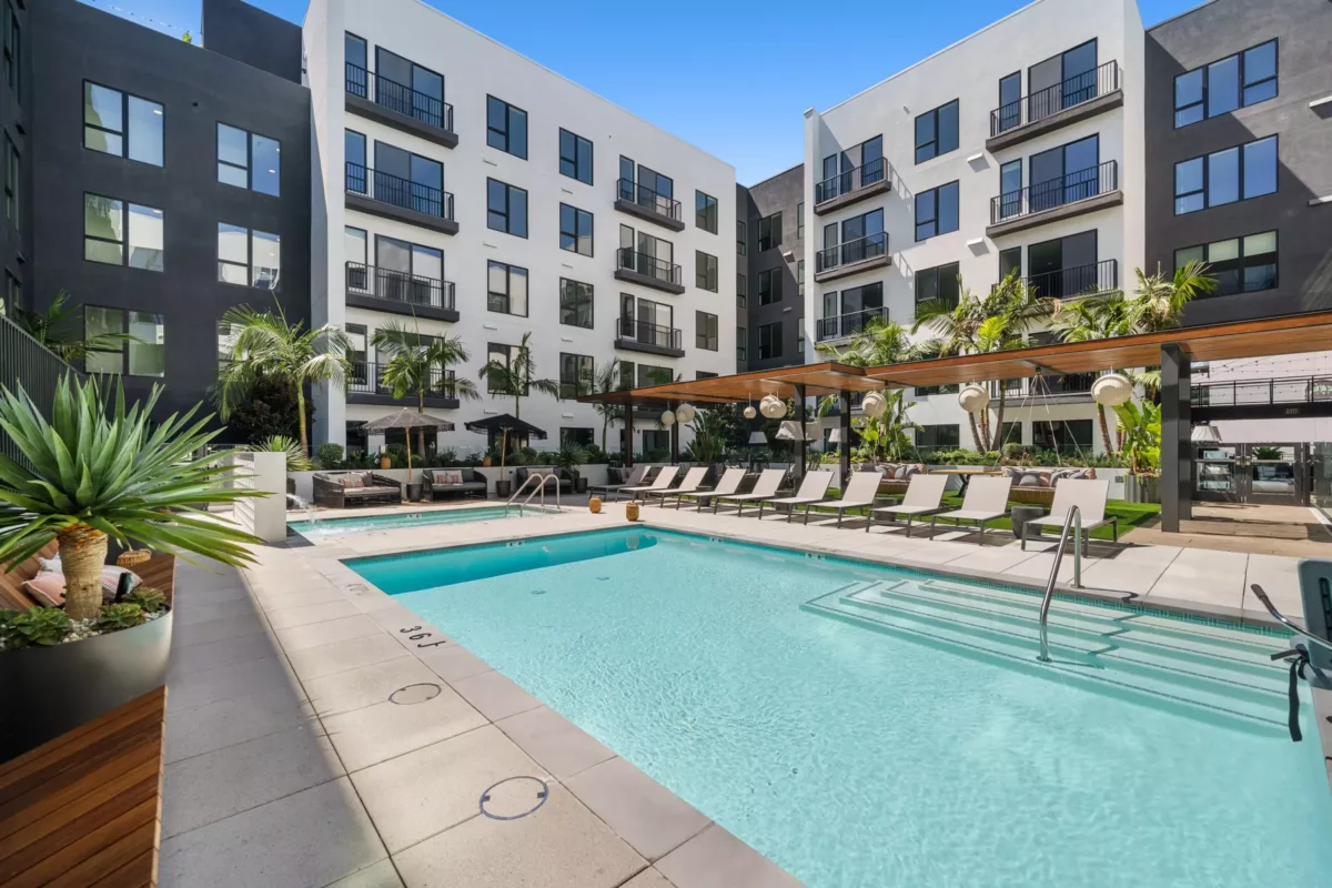 Pool surrounded by lounge chairs in the courtyard of an apartment building.