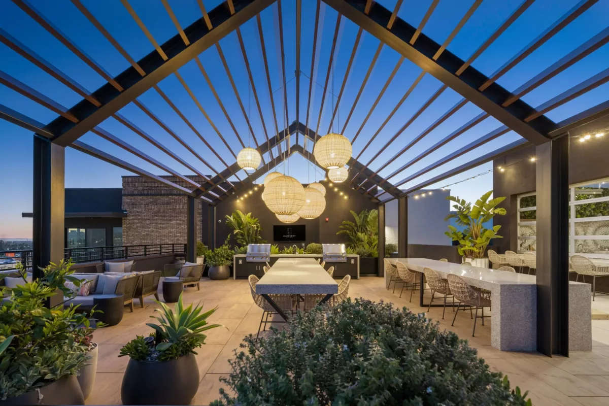 Rooftop lounge with bar under a pergola with hanging lights.