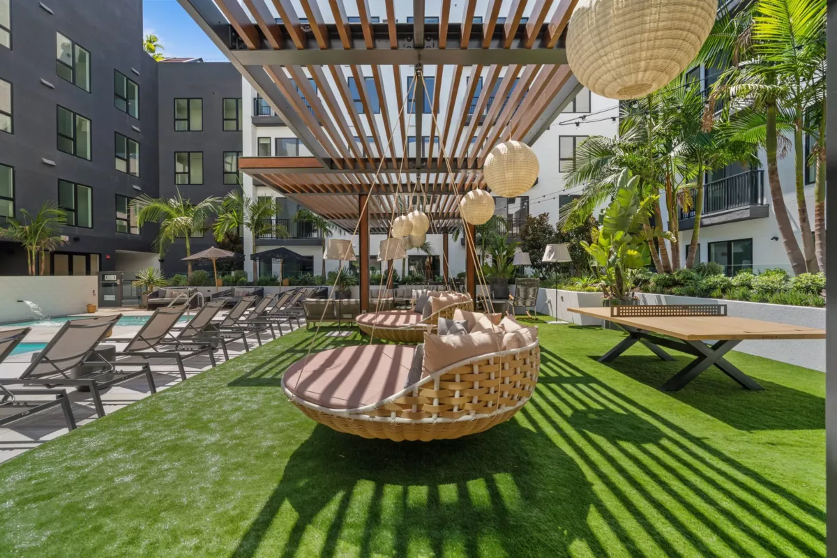 Outdoor lounge with large circular chairs beneath a pergola and hanging lights.