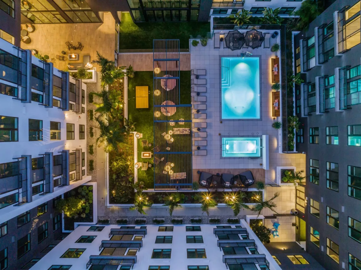 Aerial view of an apartment building courtyard with a pool and outdoor lounge seating.
