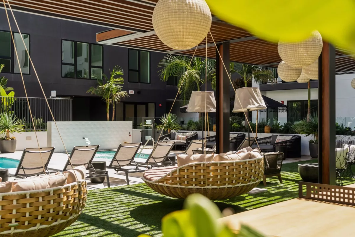 Outdoor lounge area with lounge chairs as well as hanging seating under a pergola.