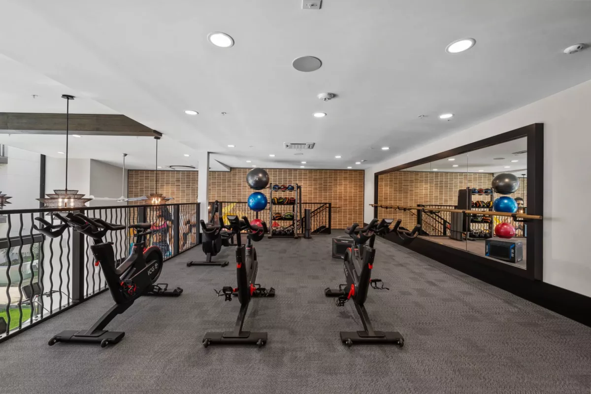 Two-story fitness center with cardio equipment and colorful mural on the far wall
