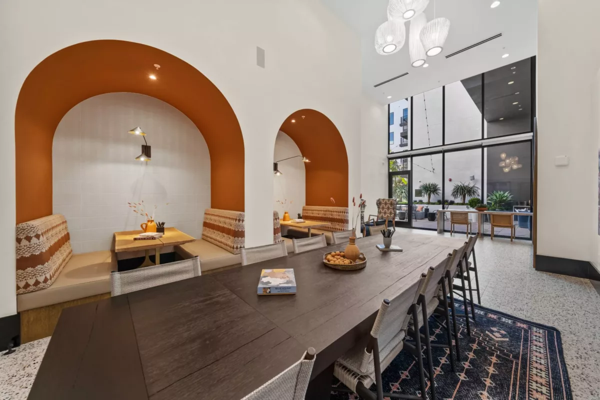 Lounge with a long table with chairs with booth seating set into the wall under curved ceilings.