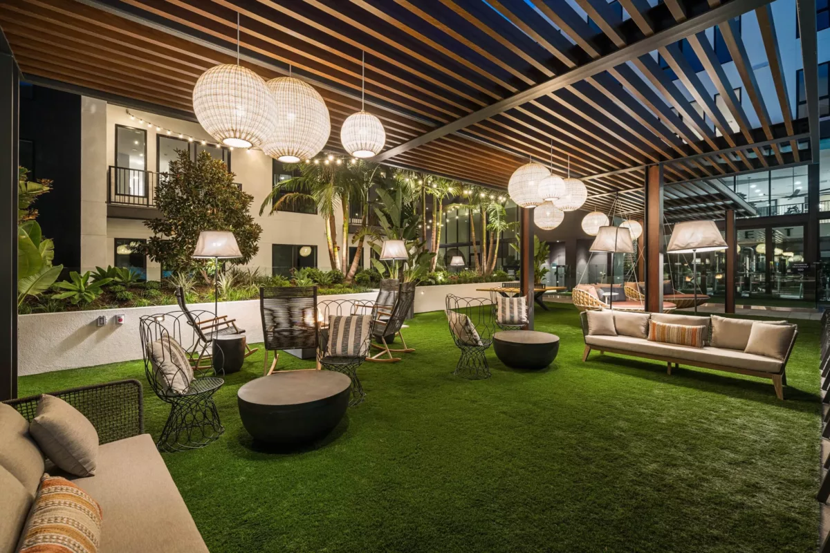 Outdoor lounge with large circular chairs beneath a pergola and hanging lights.