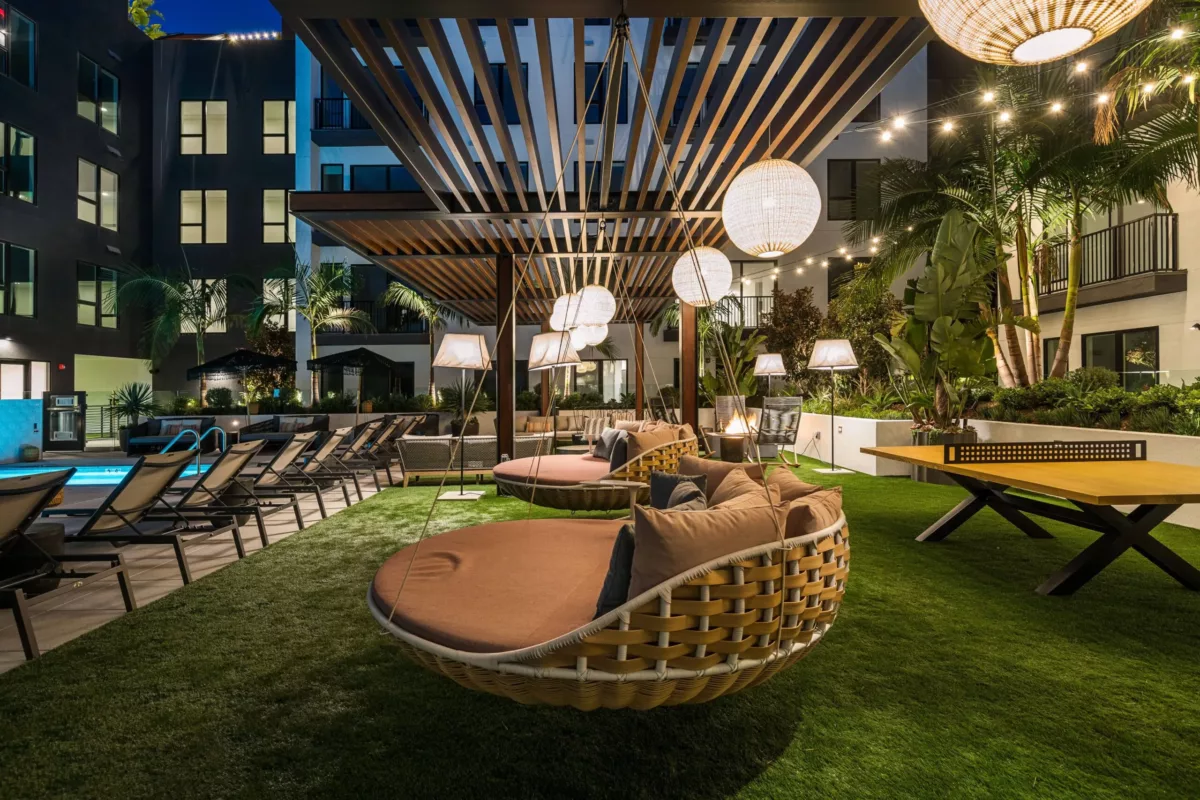 Outdoor lounge with large circular chairs beneath a pergola and hanging lights.