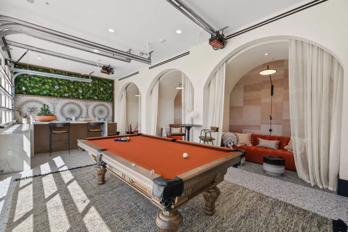 Lounge with pool table and private seating areas with rounded entrances and white curtains hung over them.