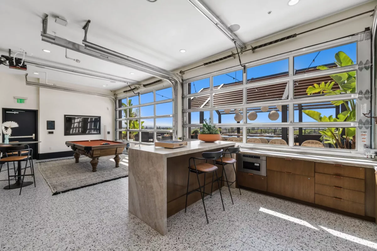 Lounge with bar in the foreground, pool table in the background, and retractable glass wall.