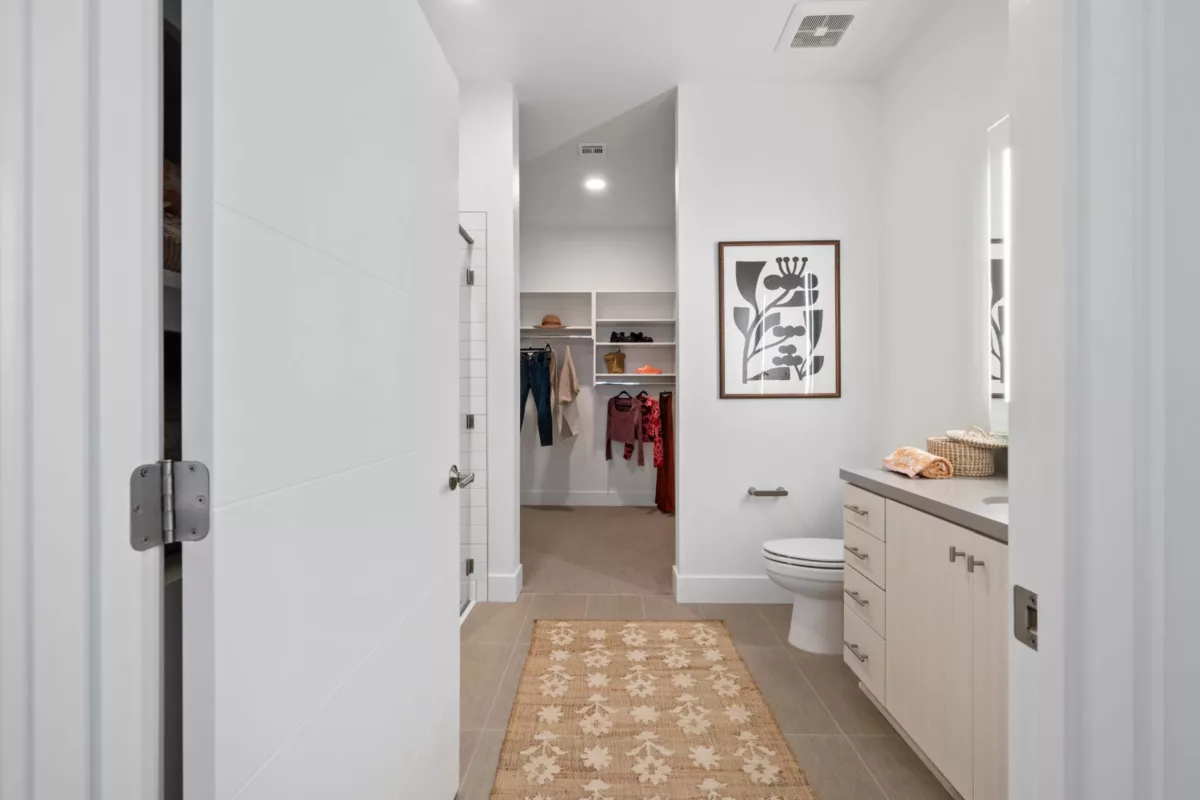 A view through a doorway into a bathroom with light-colored vanity, with a closet visible in the background.