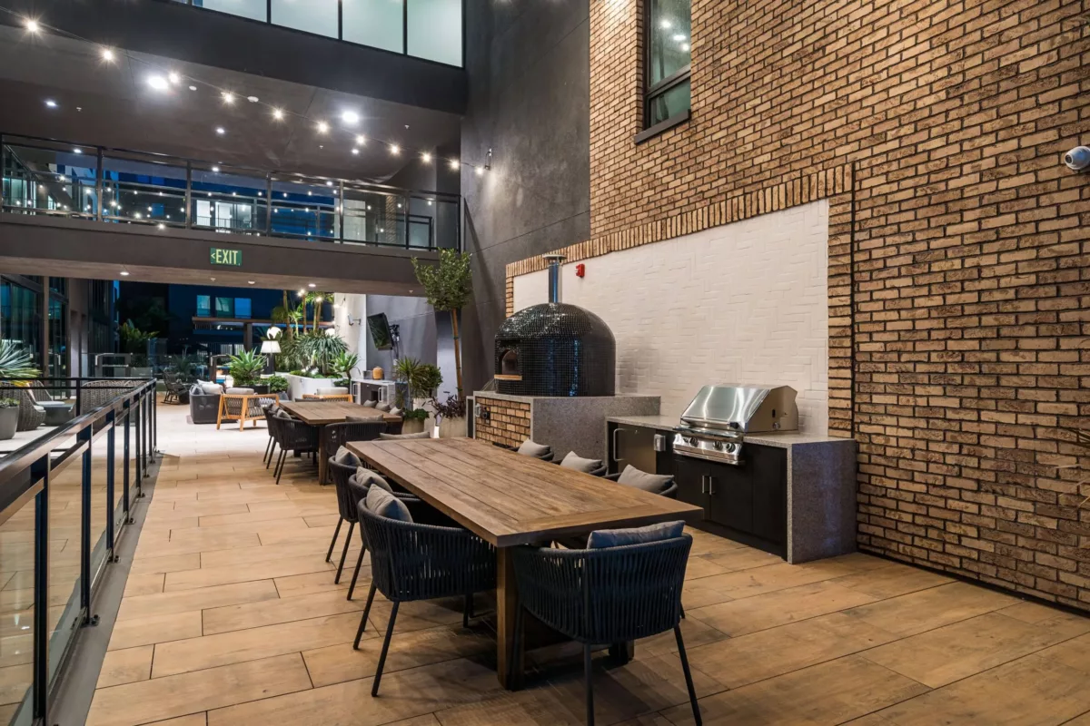 Outdoor kitchen with long table with chairs and a pizza oven.